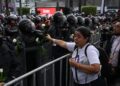 Madre buscadora entrega rosas blancas a granaderos durante protesta por desaparecidos en el Mundial