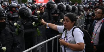 Madre buscadora entrega rosas blancas a granaderos durante protesta por desaparecidos en el Mundial